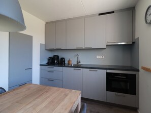 A compact kitchen with grey cabinets, a black coffee maker, a sink, and a dishwasher.