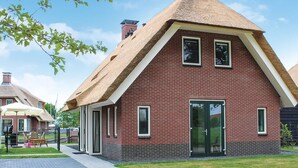 Une maison en briques avec un toit de chaume, une porte d’entrée et des fenêtres.
