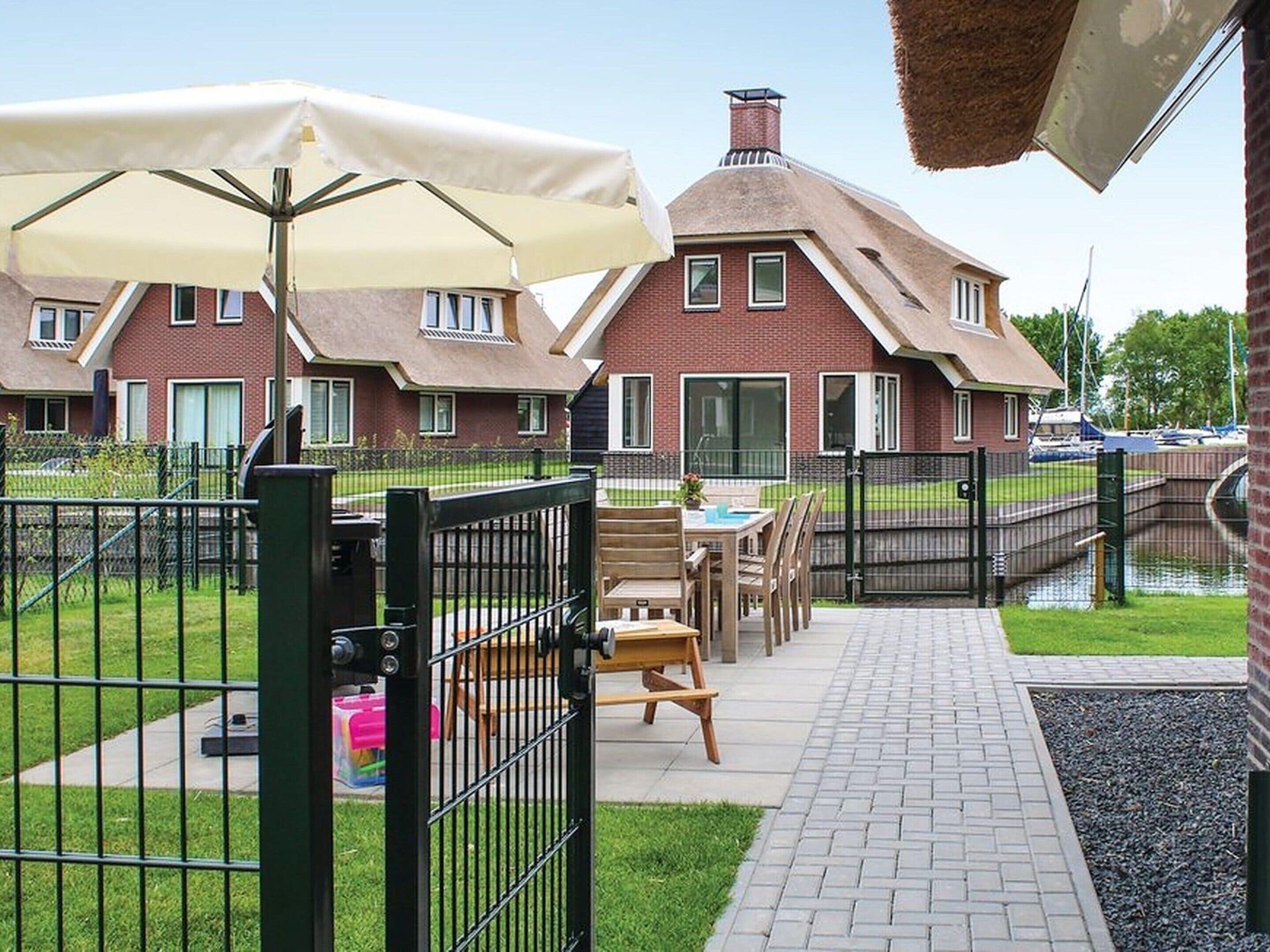 A patio area with outdoor seating, a brick building in the background, and a canal view.
