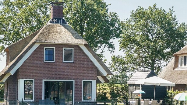 Une maison traditionnelle en briques, dotée d’un toit à forte pente et d’une cheminée.