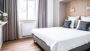 A modern bedroom with a large bed, grey curtains, a wooden headboard, and a window with a view. - Luxury & Design With sea View (Kuehlungsborn)