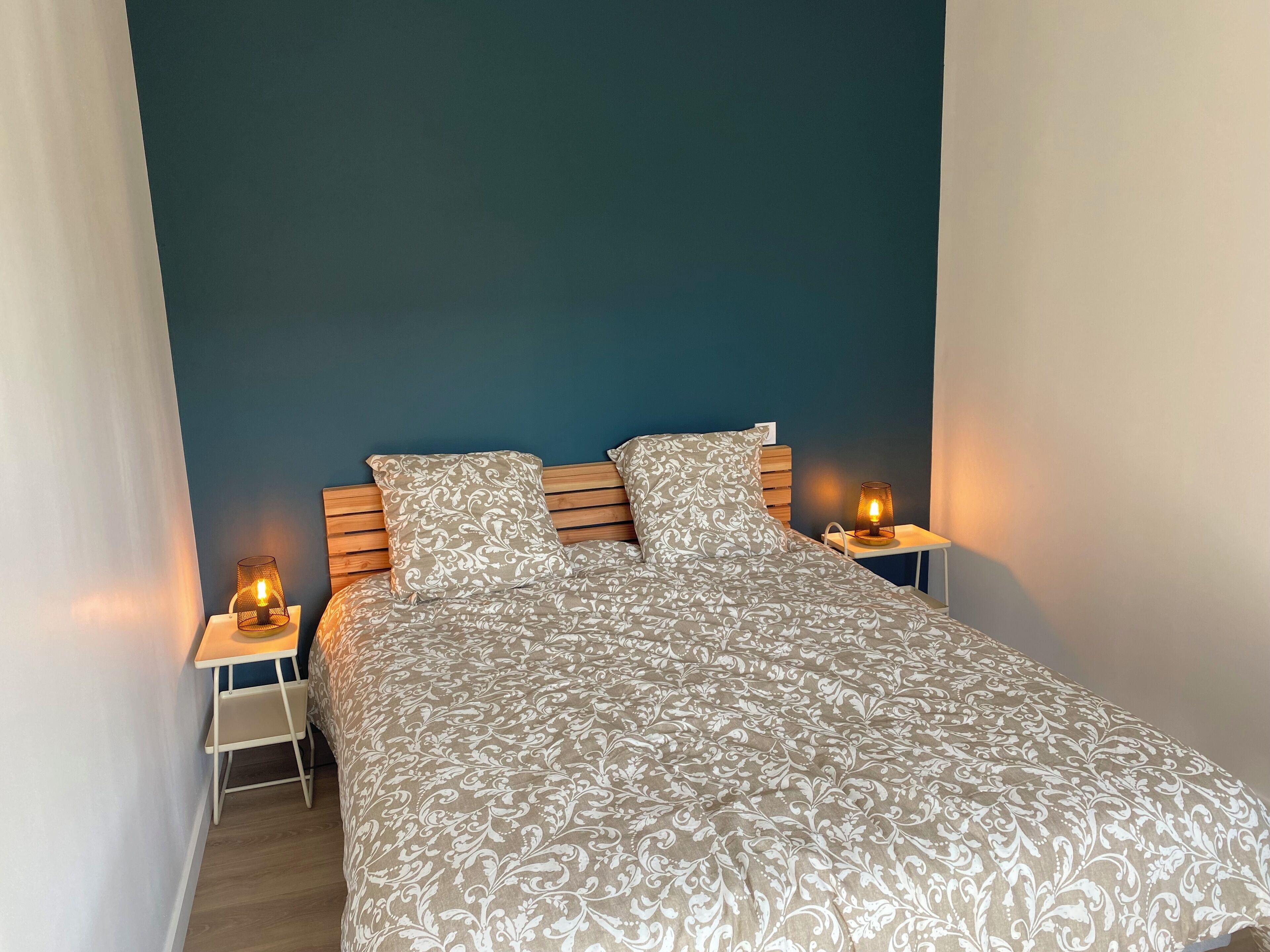 Un dormitorio con una cama, dos mesitas de noche y dos lámparas de pared.