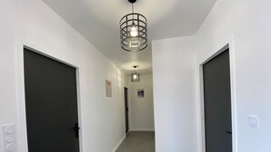 En hall med vita väggar, mörka dörrar och en lampa.