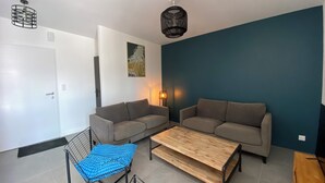 Ett modernt vardagsrum med två soffor, ett soffbord i trä och en blå kudde med mönster.