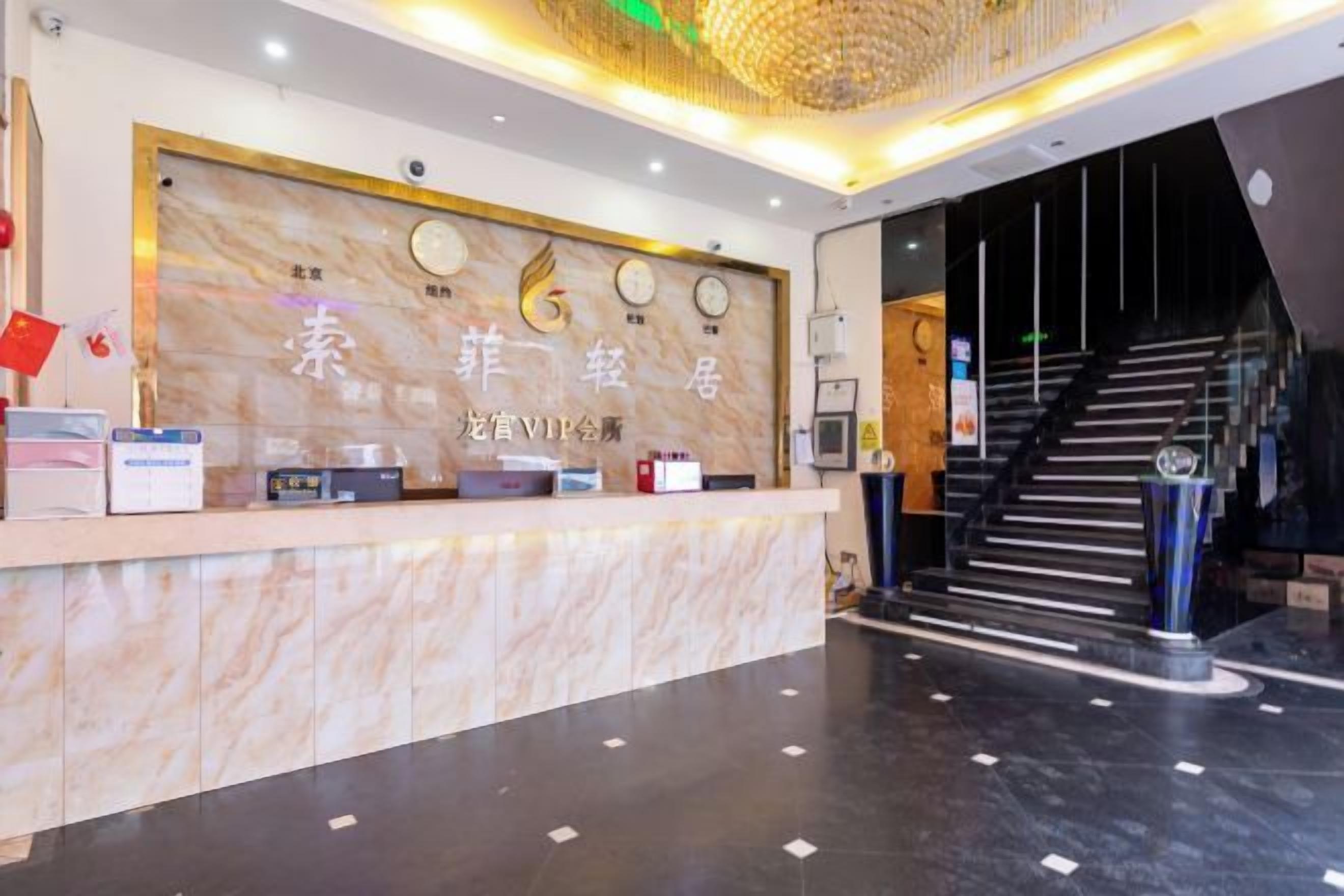 A hotel reception area with a marble counter, a staircase, and a modern interior design.