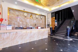A hotel reception area with a marble counter, a staircase, and a modern interior design. - SHENZHEN FEIYOUMEI HOTEL (Shenzhen)