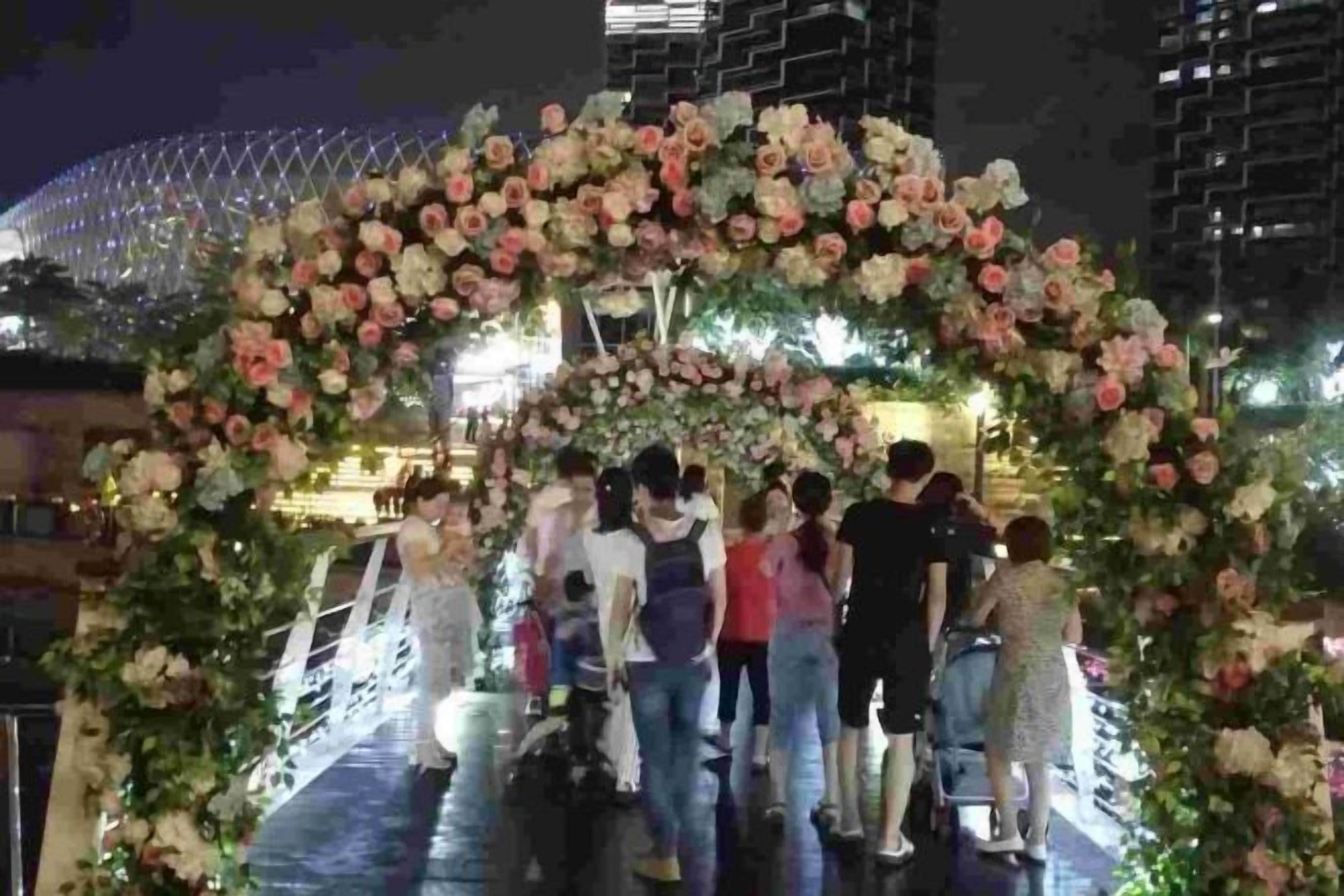A group of people standing under a floral archway.