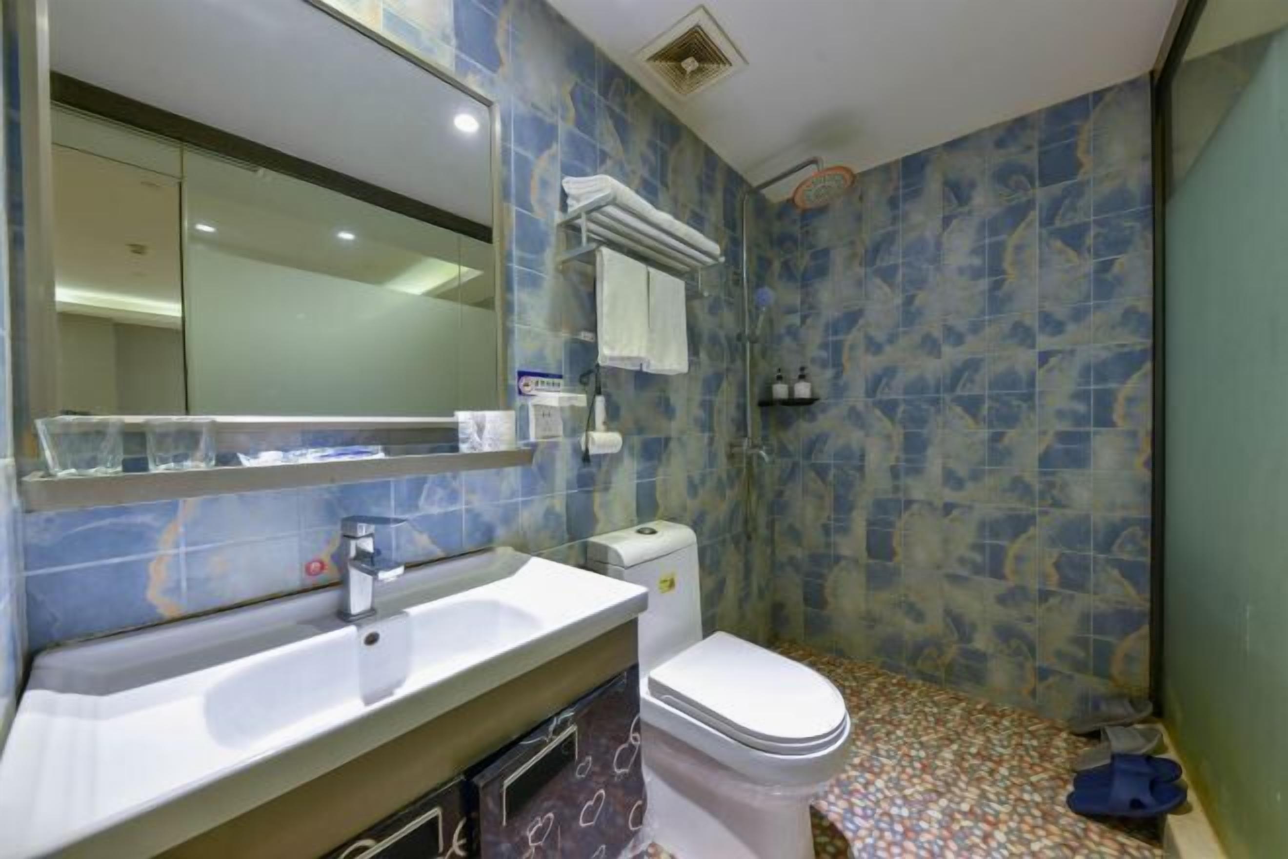 Un baño con lavabo, espejo, inodoro y zona de ducha.