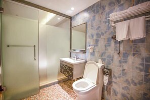 Un baño con mampara de vidrio, inodoro, lavamanos y toallero.