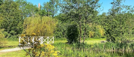 A park with a white metal fence, lush greenery, and a clear blue sky.