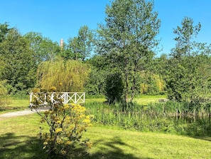 Un parc avec une clôture en métal blanc, une végétation luxuriante et un ciel bleu dégagé.