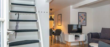 A modern living room with a staircase, a television, and a sofa.