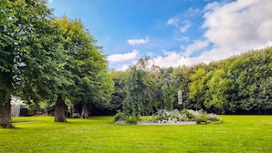 A well-maintained park with a variety of trees, a central flower bed, and a clear sky. - 4 Person Holiday Home in Tonder-by Traum (Tonder)