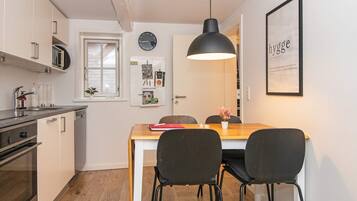 Una cocina moderna con comedor, que incluye una mesa de madera, dos sillas, una lámpara colgante y un reloj en la pared.