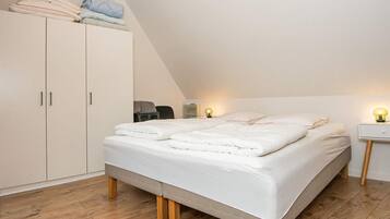 A bedroom with a bed, a wardrobe, and a nightstand with a lamp.