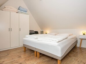 Et soveværelse med en seng, et skab og et natbord med en lampe.