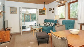 A cozy living room with a teal sofa, a wooden dining table, and a large window. - 5 Person Holiday Home in Rorvig (Rørvig)