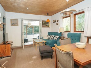 A cozy living room with a teal sofa, a wooden dining table, and a large window. - 5 Person Holiday Home in Rorvig (Rørvig)