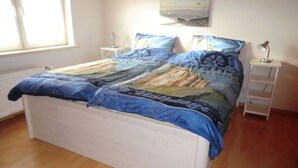 A bedroom with a bed, two bedside tables, a window, and a wall-mounted picture. - Lutje Carolinensiel Harlesiel (Wittmund)