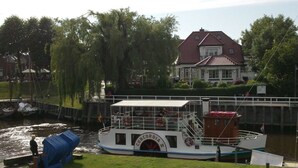 A boat docked near a grassy area with a house in the background. - Lutje Carolinensiel Harlesiel (Wittmund)