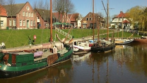 A row of boats docked along a calm waterway, with houses and a grassy area in the background. - Lutje Carolinensiel Harlesiel (Wittmund)