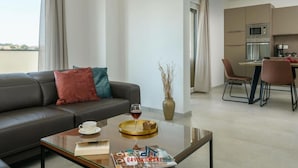 A modern living room with a sofa, coffee table, and a dining area with a kitchen in the background. - Villa Dora - Apt 4 "bruin" (Pula)
