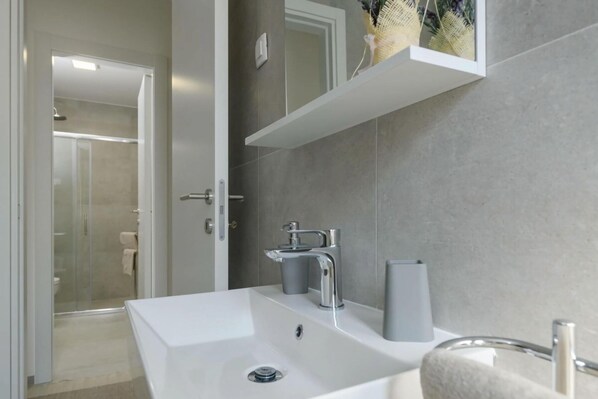 A modern bathroom with a white sink, a glass shower enclosure, and a towel rack. - Villa Dora - Apt 4 "bruin" (Pula)