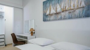 A hotel room with a bed, a chair, a desk, a lamp, and a painting of sailboats on the wall. - Villa Dora - Apt 4 "bruin" (Pula)