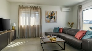 A modern living room with a sofa, a coffee table, a TV, and a painting on the wall. - Villa Dora - Apt 4 "bruin" (Pula)