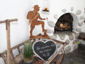A rustic interior with a stone fireplace, a metal sculpture of a hiker, and a wooden bench with a heart-shaped sign. - Hochkalter - Reich Family (Schoenau am Koenigssee)