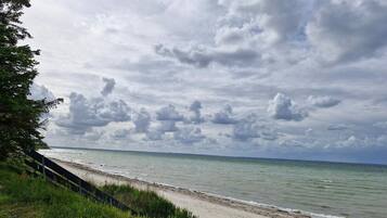 A beach with a grassy foreground and a cloudy sky.