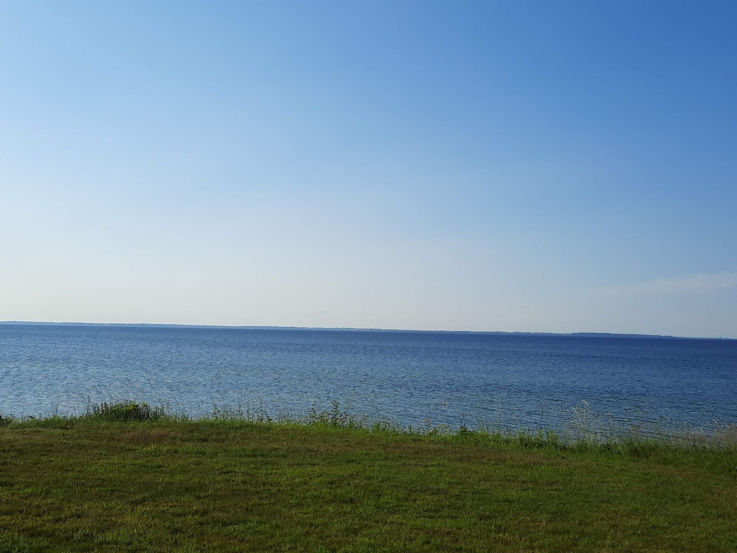 A clear view of a calm sea with a distant shoreline.