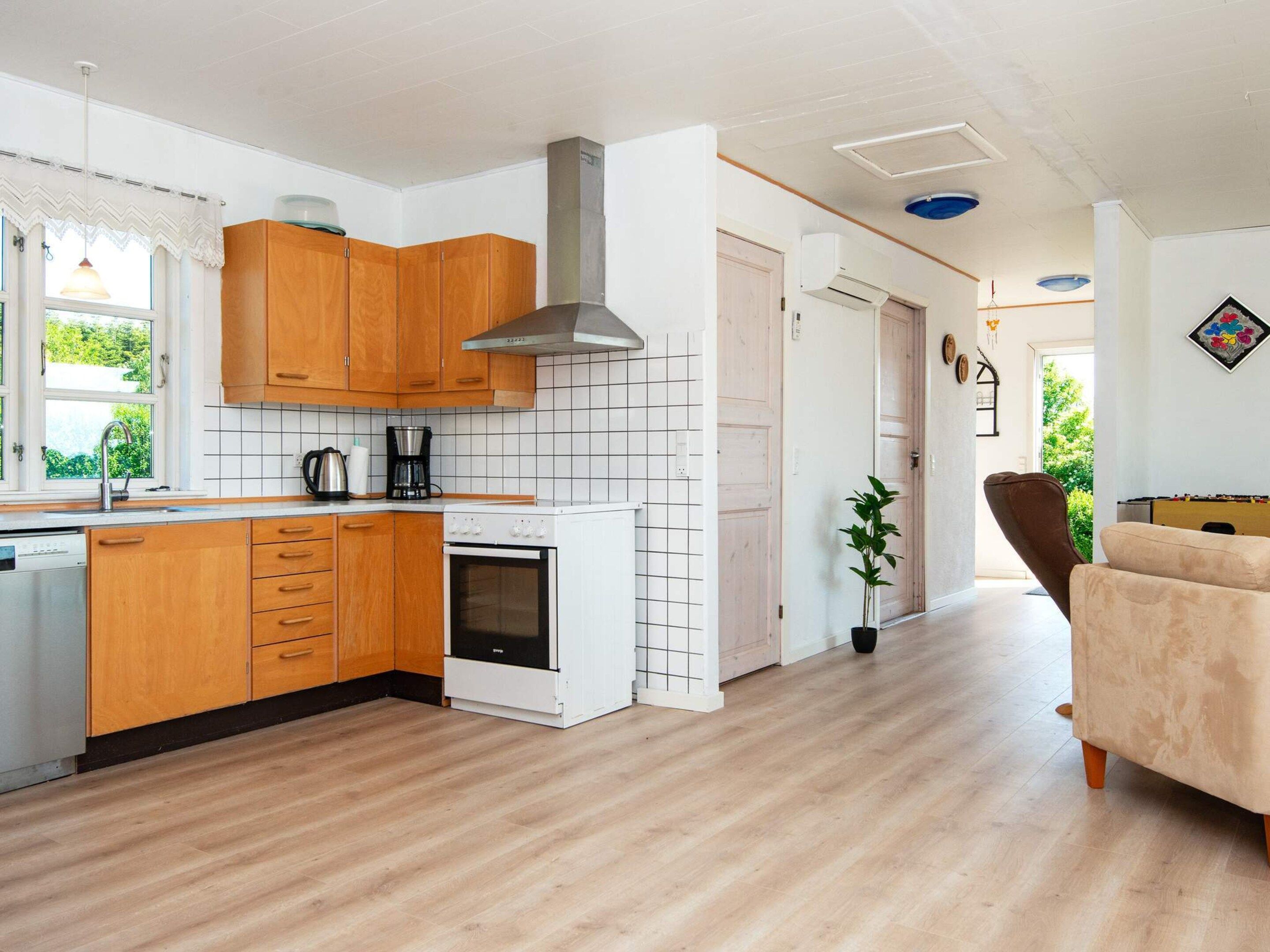 Eine moderne Küche mit Holzschränken, einem eingebauten Ofen und einer weißen Fliesenrückwand.