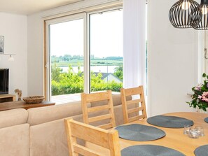 A dining area with a table set for four, a sofa, and a TV in the background. - 6 Person Holiday Home in Nordborg (Nordborg)