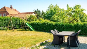 A patio area with a table and chairs, a swing set, and a slide. - 6 Person Holiday Home in Nordborg (Nordborg)
