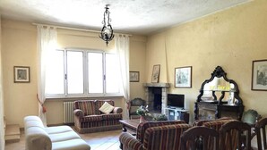 Uma sala de estar com lareira, televisão e uma área de jantar com cadeiras e mesa.
