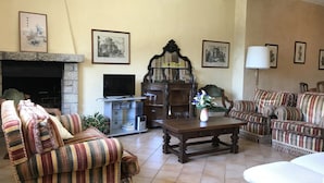 Uma sala de estar com lareira, televisão e mesa de jantar.