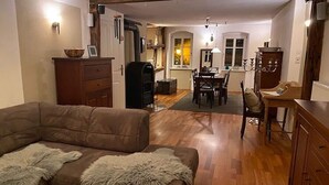 Un salon chaleureux avec un canapé marron, un meuble en bois et un coin repas comprenant une table et des chaises.
