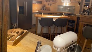 Une cuisine compacte équipée d’un réfrigérateur, d’un four à micro-ondes, d’une machine à café et d’un petit coin repas avec deux tabourets.
