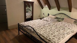 Une chambre à coucher comprenant un lit, une table de chevet, un miroir et une lampe fixée au mur.