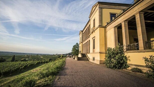Un bâtiment avec un chemin pavé menant à une grande entrée ornée de colonnes.