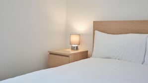 A neatly made bed with white linens and a wooden headboard. - Apartment 3 in Loftus (Saltburn-by-the-Sea)