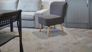 A modern living room with a grey sofa, a black chair, and a grey cabinet. - Apartment 3 in Loftus (Saltburn-by-the-Sea)