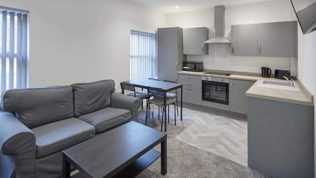 A modern, compact living space with a grey sofa, a dining table, and a kitchenette. - Apartment 3 in Loftus (Saltburn-by-the-Sea)