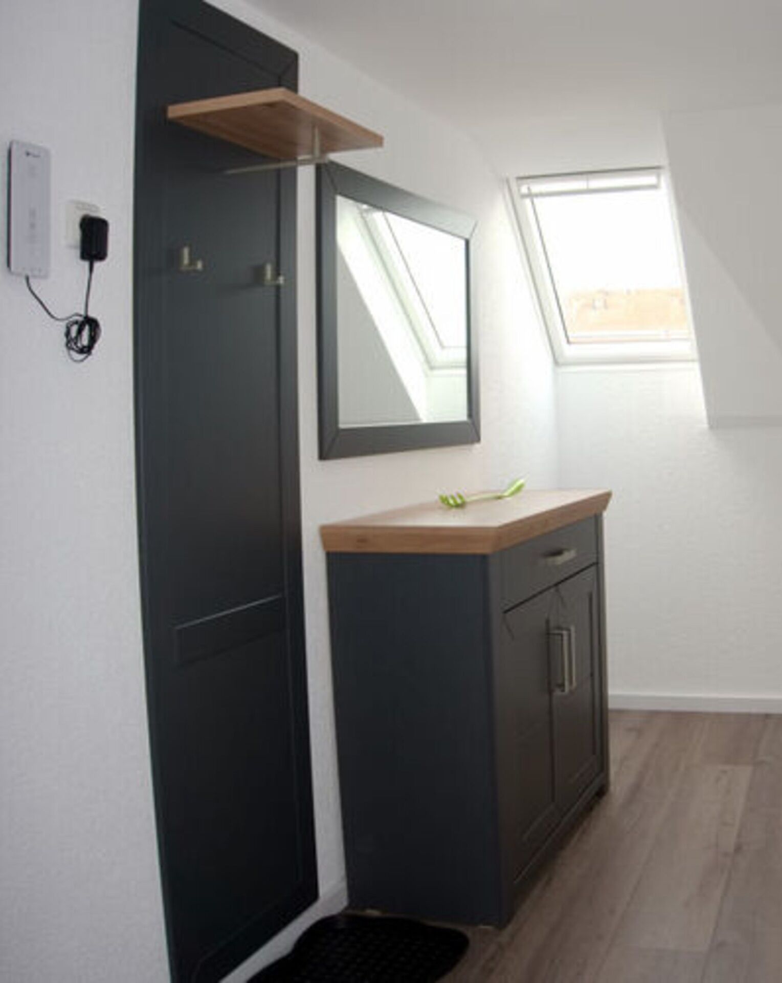 A small bathroom with a dark door, a mirror, a wooden countertop, and a window.