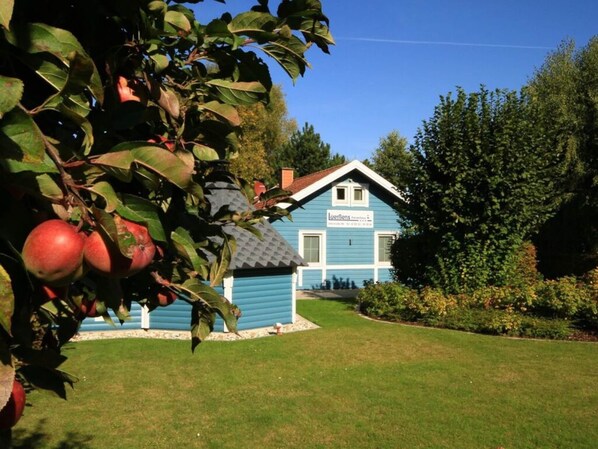A blue house with a sign that reads "Löwengarten" in front of a well-maintained lawn and trees.