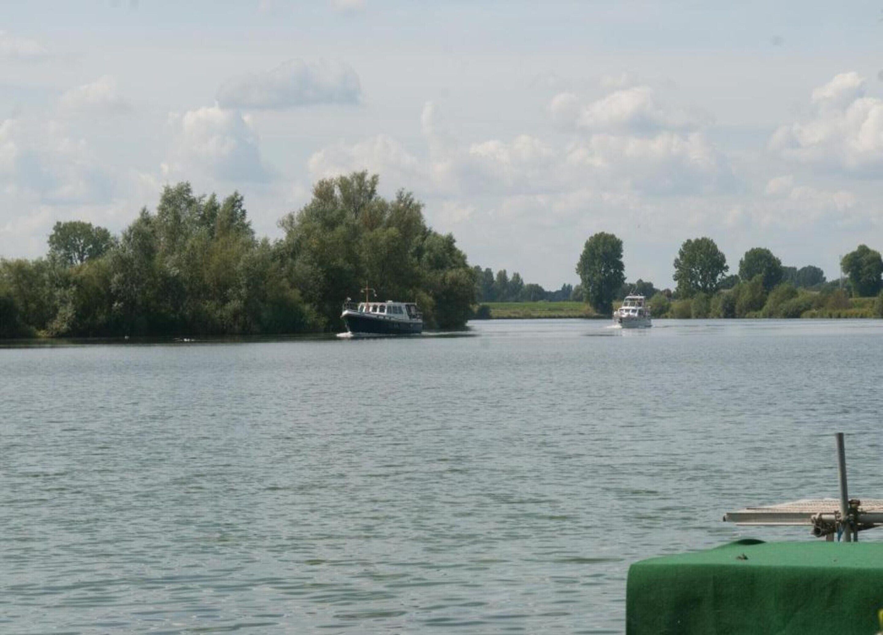 Une rivière paisible, avec des bateaux et un quai recouvert de verdure.