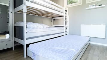 A bunk bed room with a white mattress, a lower bunk with a mattress, and a white headboard.