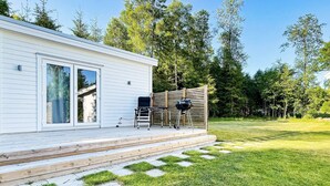 A modern house with a wooden deck, a sliding glass door, and a barbecue grill. - 3 Person Holiday Home in Ljungby (Ljungby)