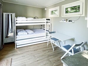 A bunk bed with a desk and chairs, a small shelf with items, and a window with a view of trees. - 3 Person Holiday Home in Ljungby (Ljungby)